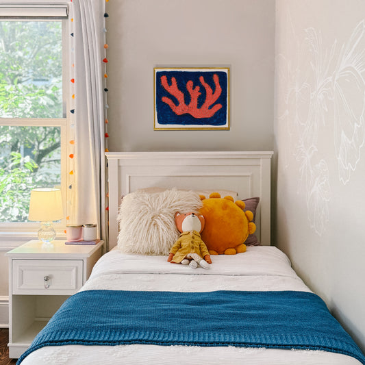 Cozy bedroom featuring a bed with a blue blanket, plush toys, and a colorful wall art piece.