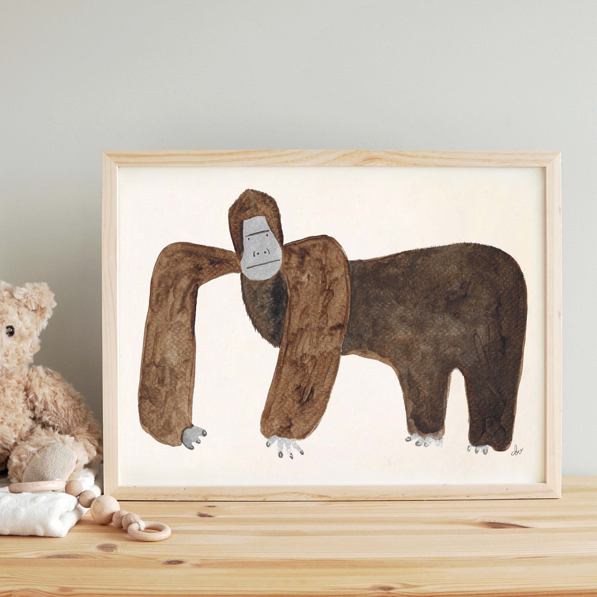 A framed illustration of a gorilla standing on a wooden surface beside a teddy bear.