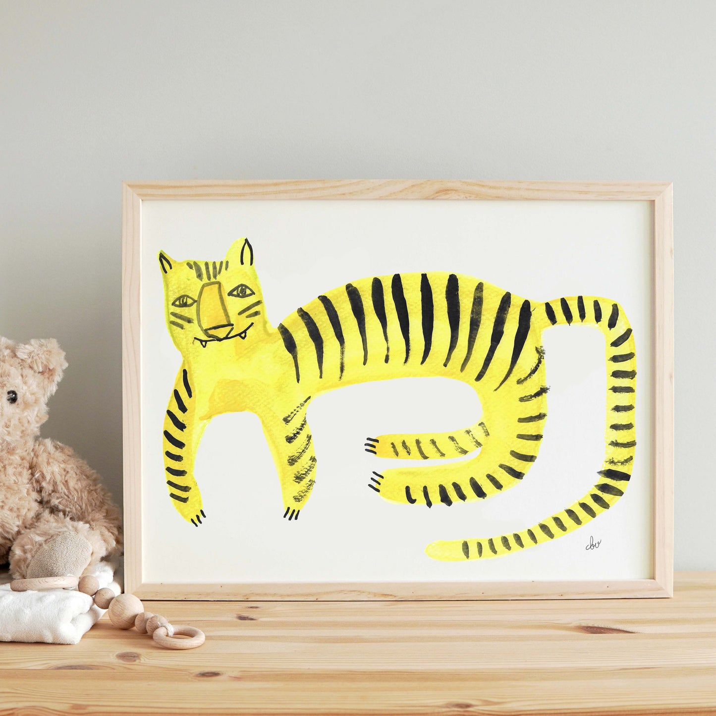 A colorful artwork of a yellow tiger with black stripes, framed and placed on a wooden surface.