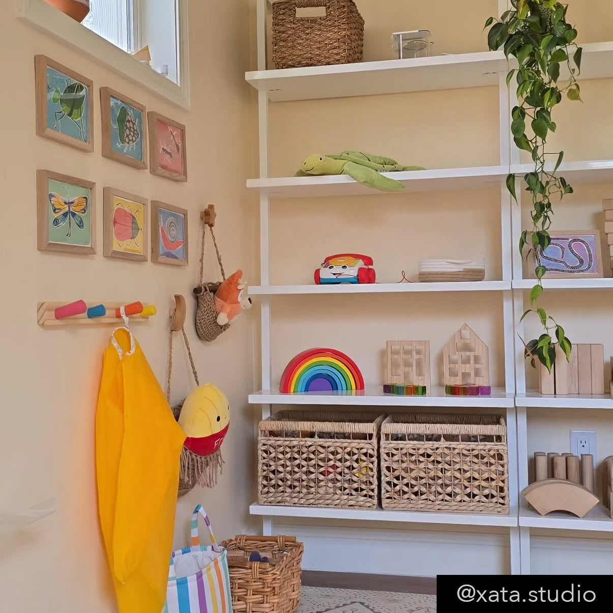 A cozy playroom featuring colorful wall art, shelves filled with toys and books, and a rainbow decoration.