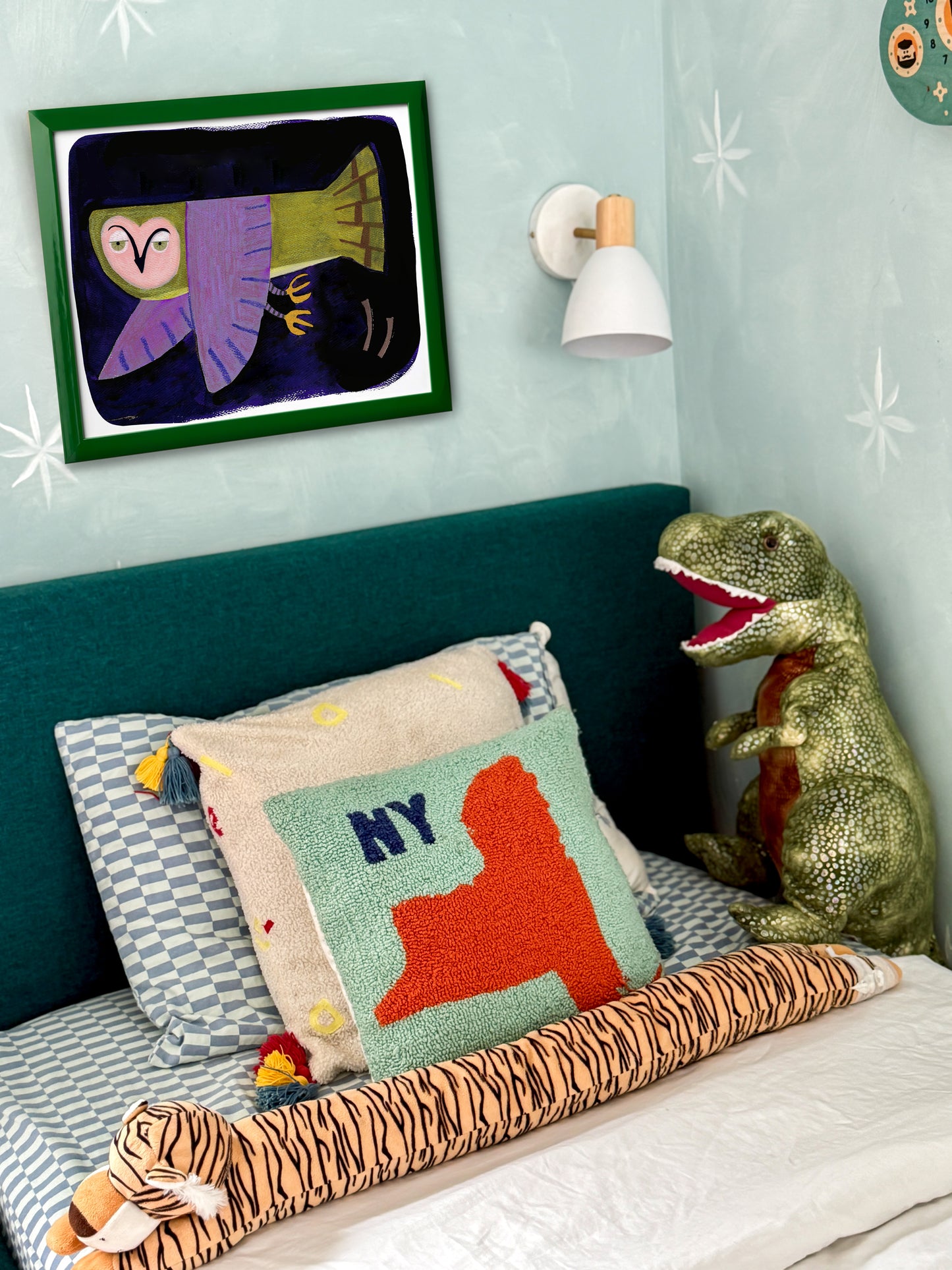 Colorful bedroom corner with decorative pillows, stuffed animals, and a framed artwork.