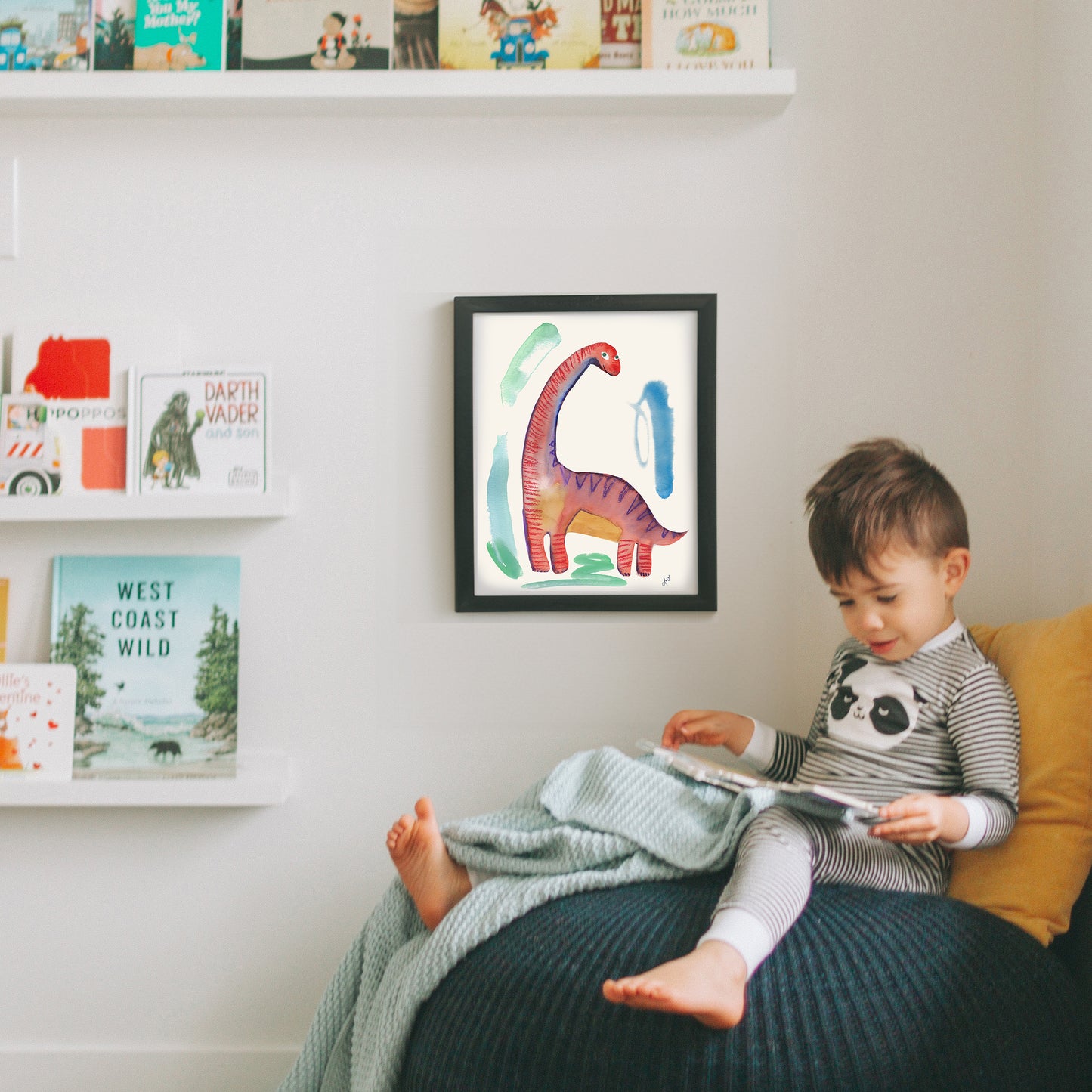 A child sitting on a cozy chair reading a book, with colorful dinosaur artwork on the wall.