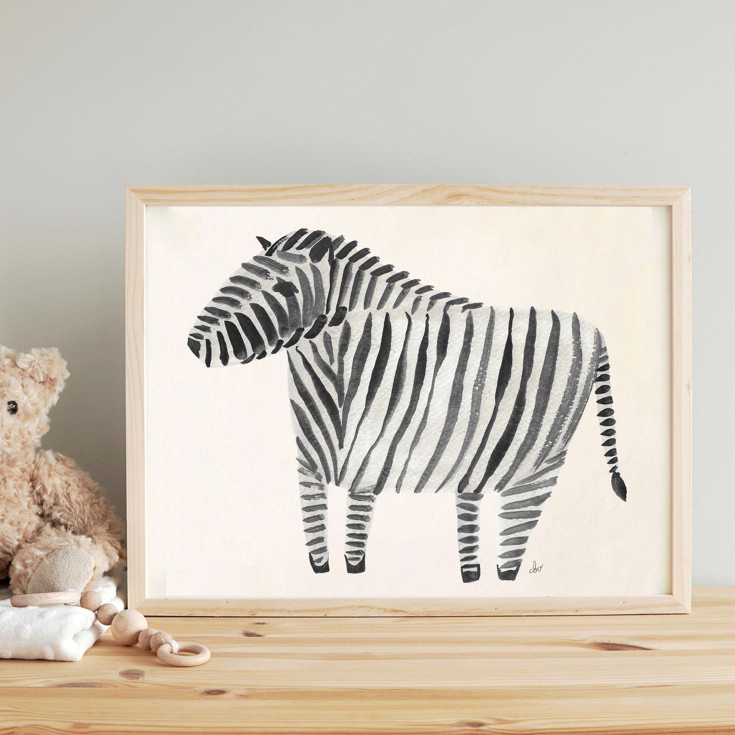 A framed illustration of a zebra with a striped pattern on a wooden table.
