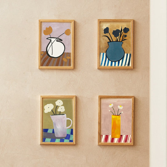 Four framed art pieces featuring abstract floral designs on a textured wall.