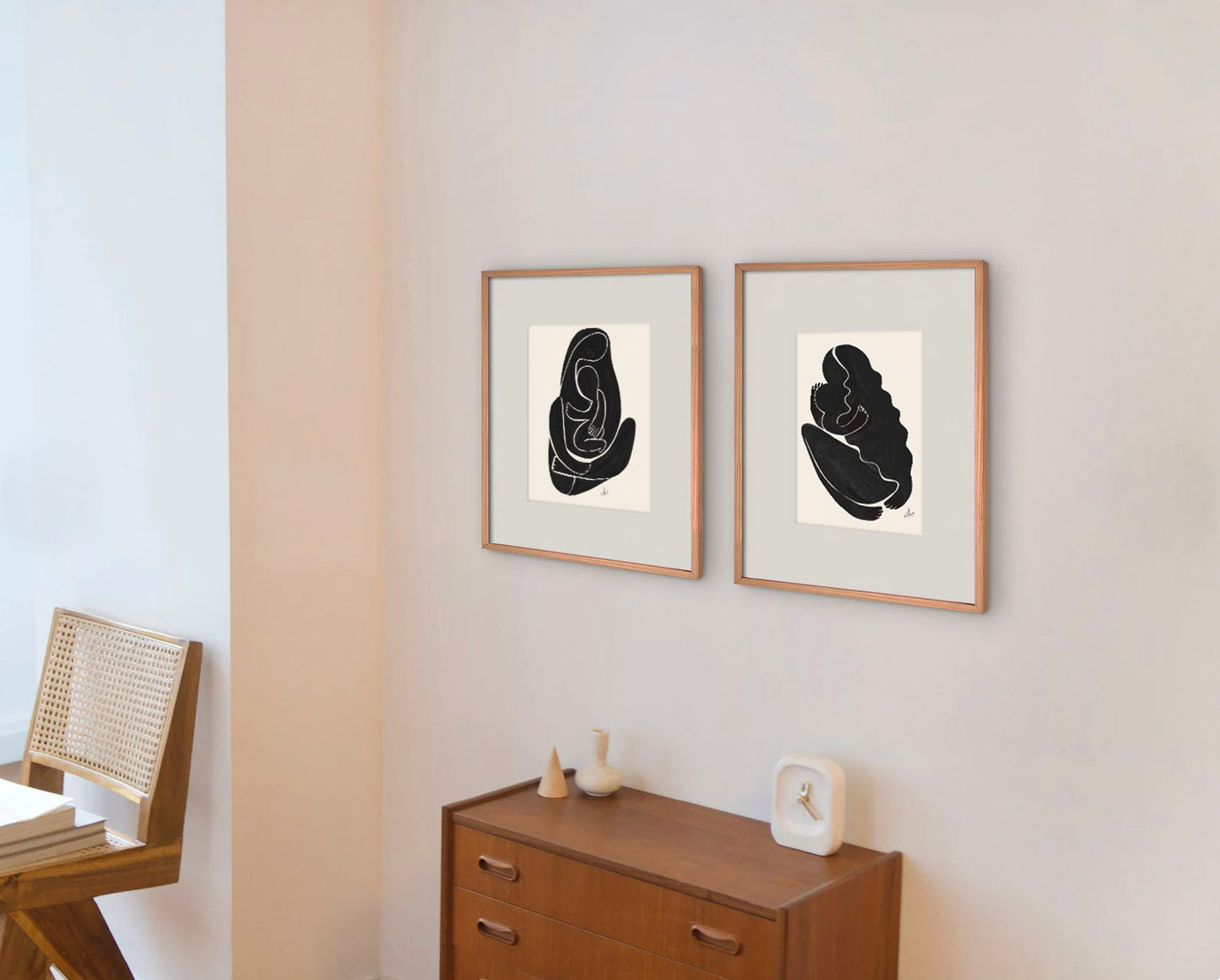 Two framed minimalist black and white art pieces hanging on a wall in a modern interior setting.