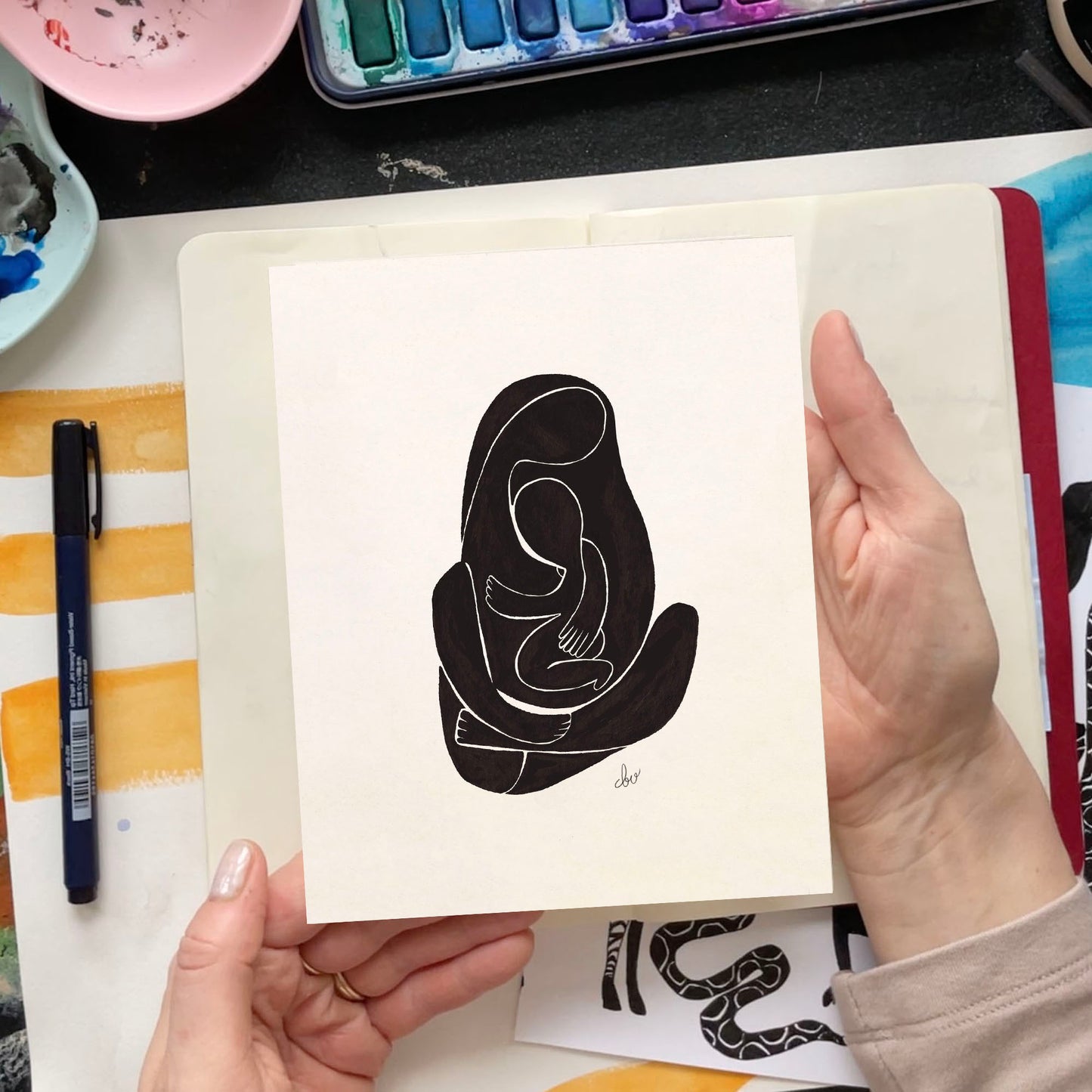 A person holding an abstract line drawing of a seated figure.