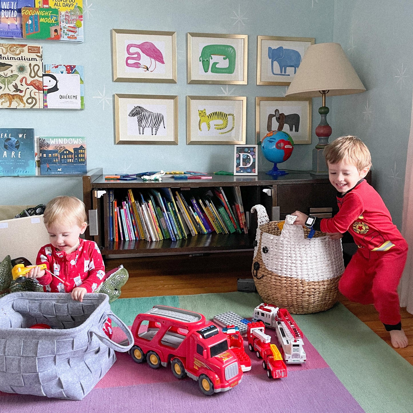 Two children playing with toys in a colorful playroom decorated with framed animal art.