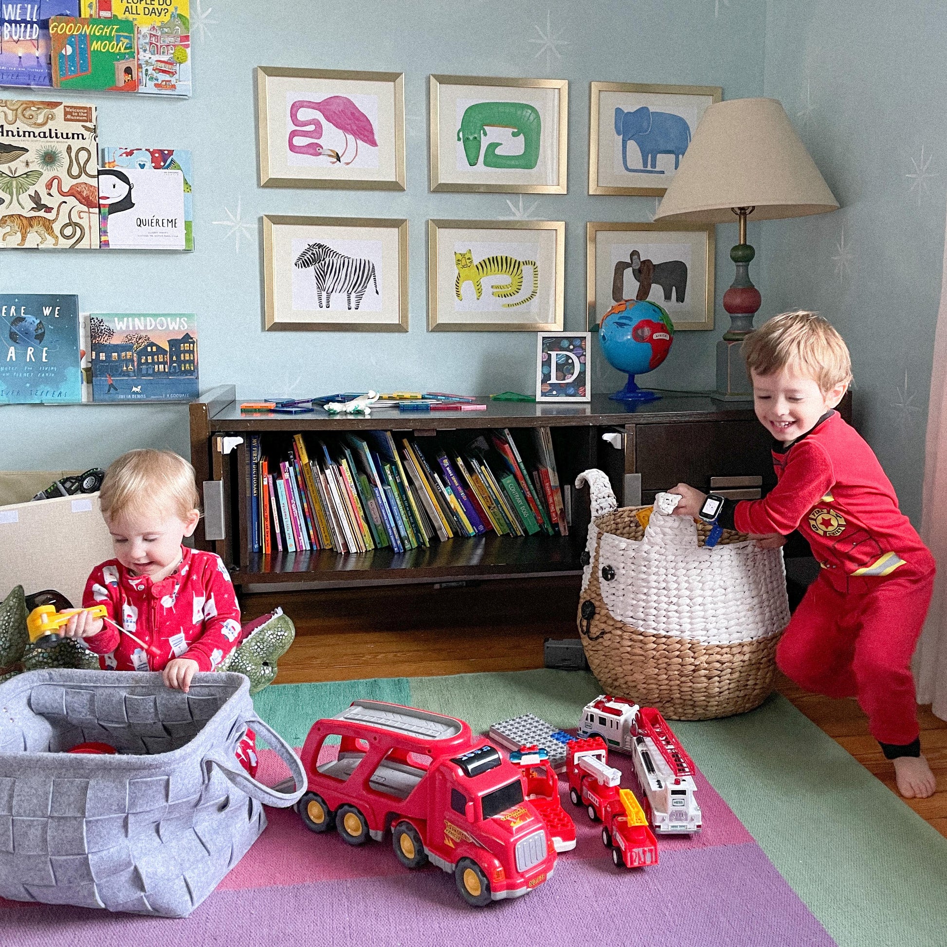 Two children playing with toys in a colorful playroom decorated with framed animal art.