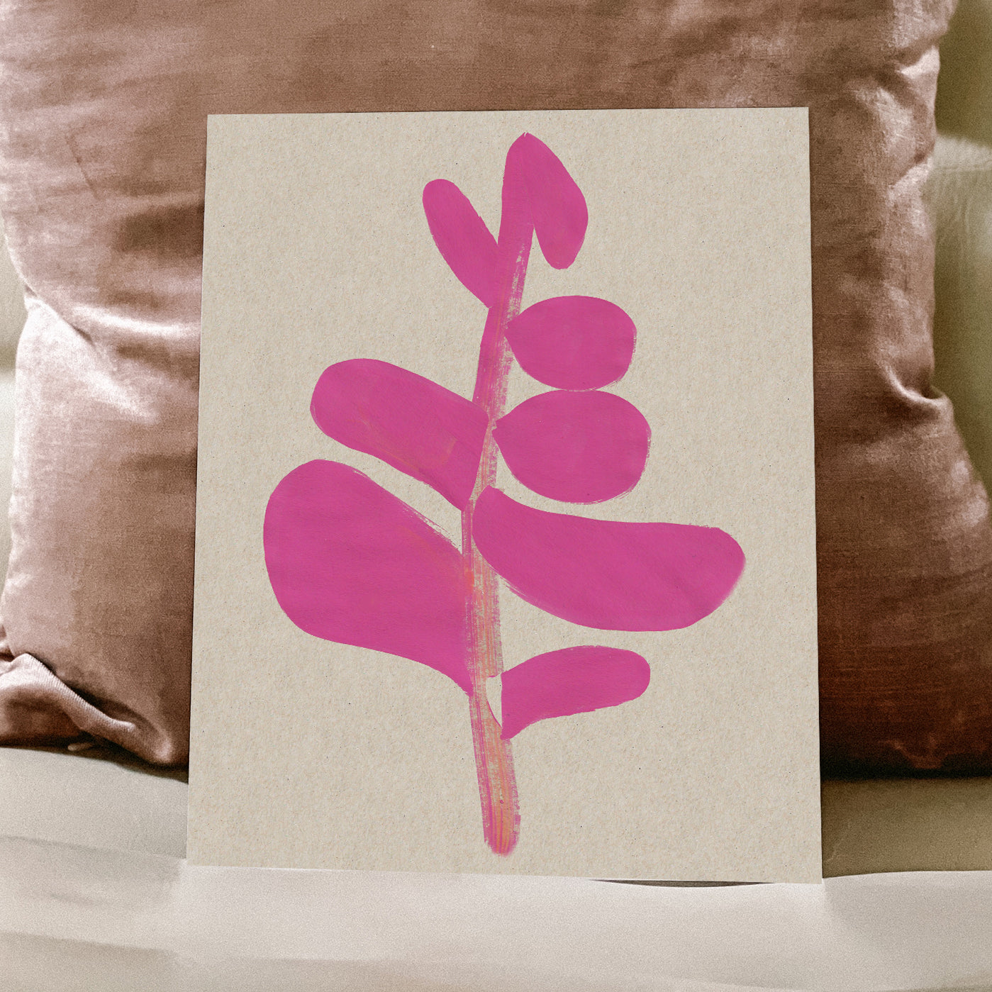 A pink abstract leaf design on a beige background placed on a sofa.