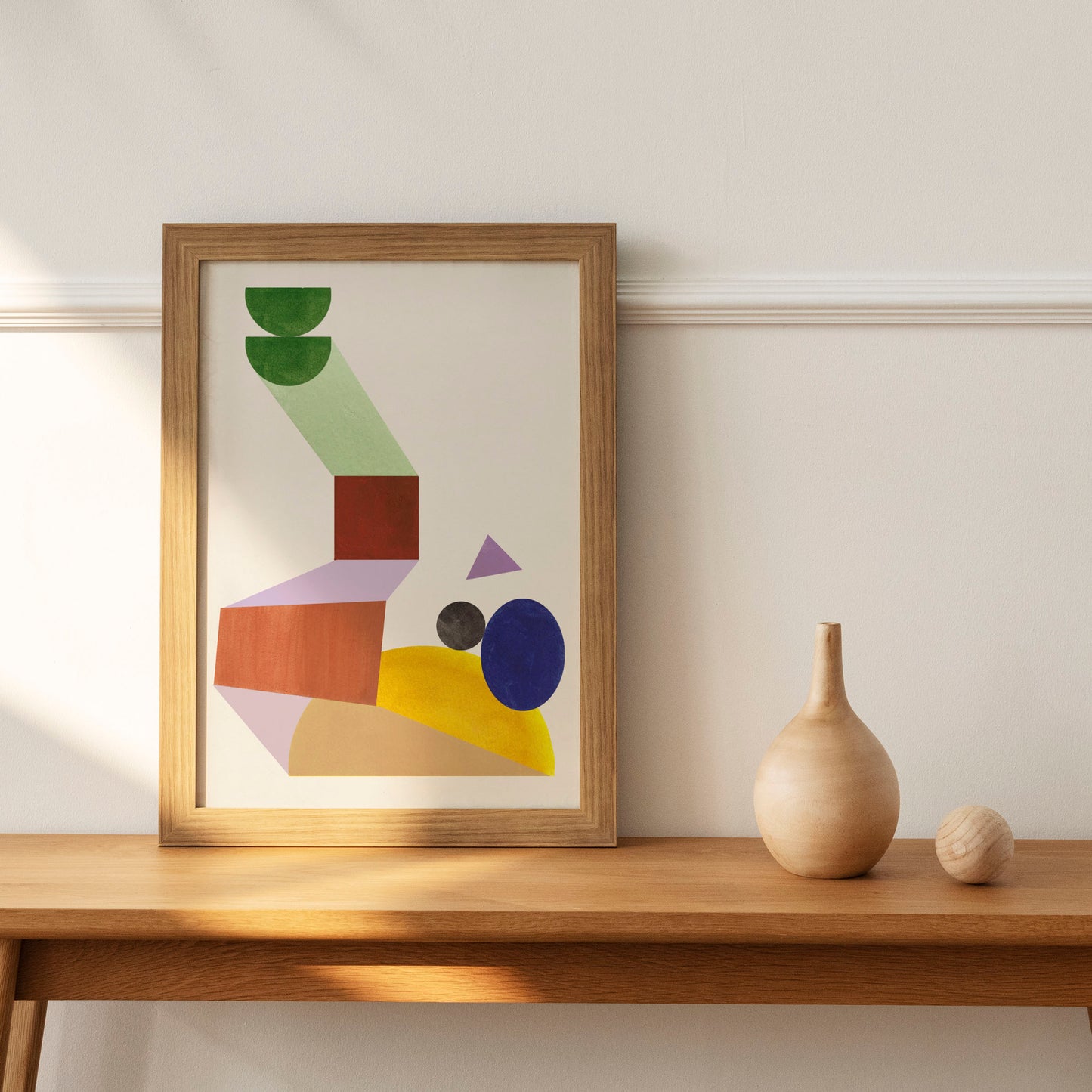 A framed abstract artwork featuring geometric shapes and colors on a wooden table.