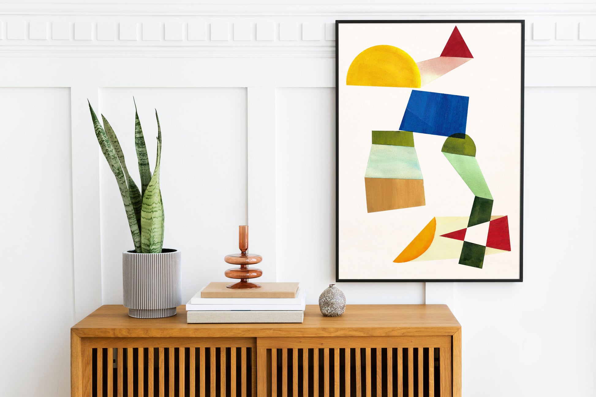 Modern interior scene featuring abstract artwork on the wall, a potted plant, and decorative items on a wooden sideboard.